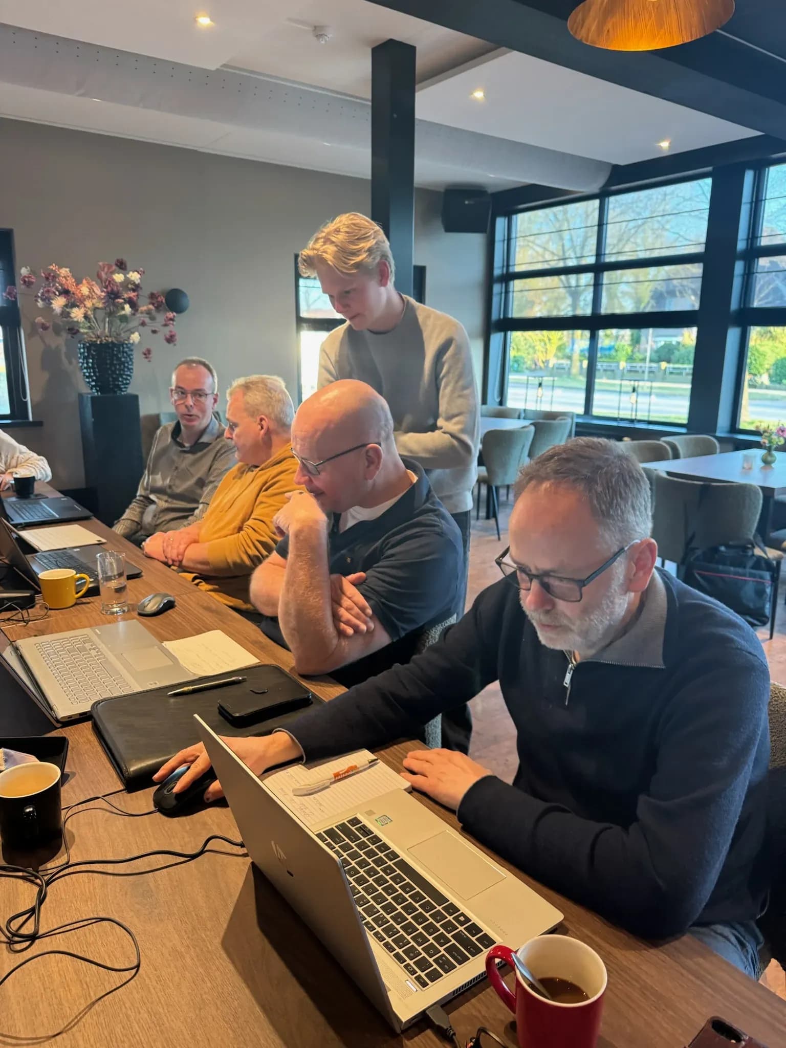 Een begeleider helpt deelnemers aan laptops