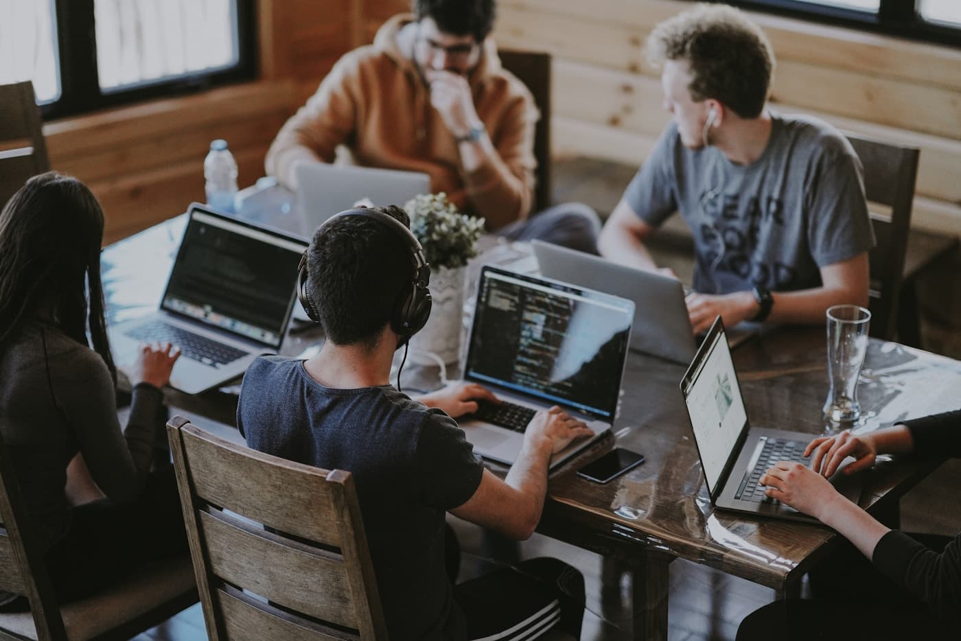 Een groep werkt samen aan laptops rond een gedeelde tafel