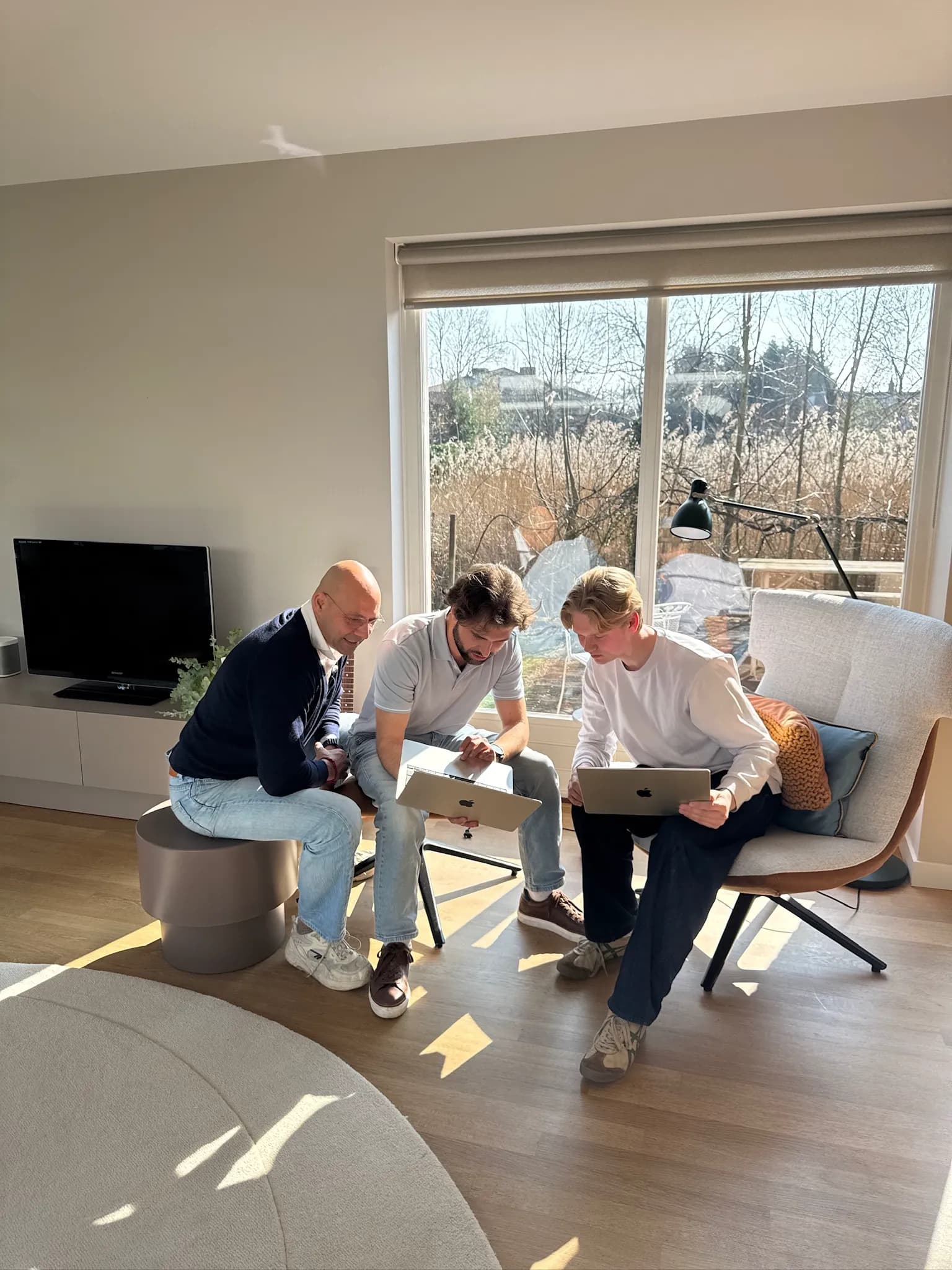 Drie collega's bespreken samen hun werk op laptops